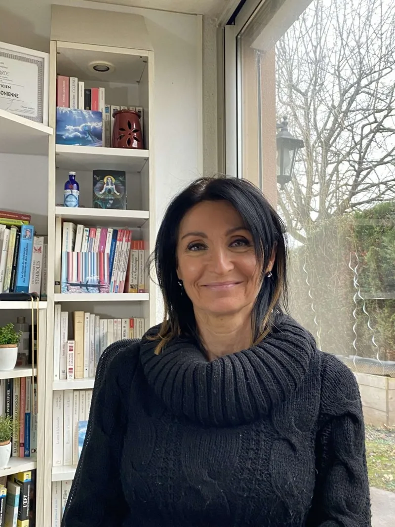 Portrait de Nathalie Narce, hypnothérapeute à Obernai, souriante devant une bibliothèque