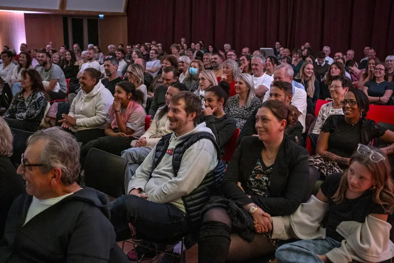 Des spectateurs de tous âges rient aux éclats pendant un spectacle d'hypnose