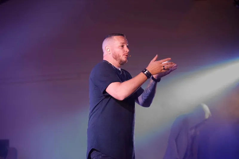 R'Key explique au public, la main tendue, dans la lumière des projecteurs