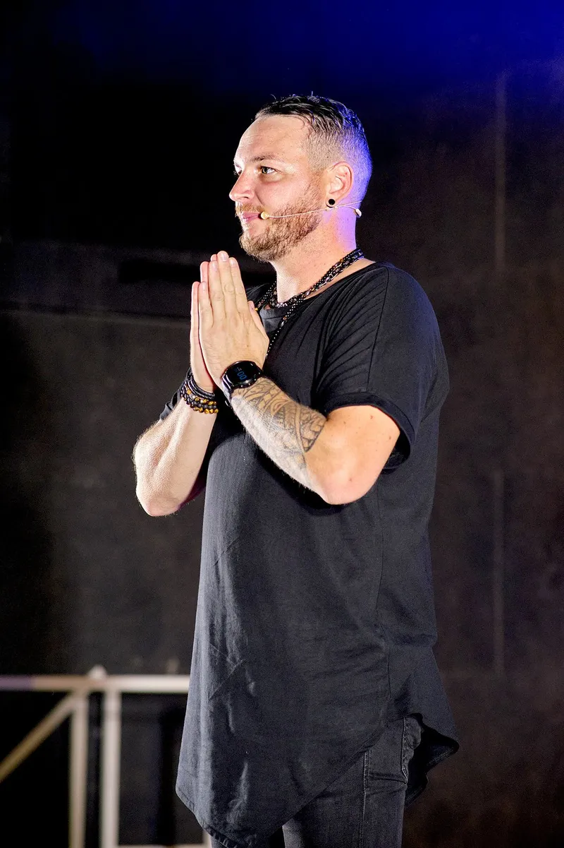 R'Key, hypnotiseur, les mains jointes sur scène, sourire aux lèvres