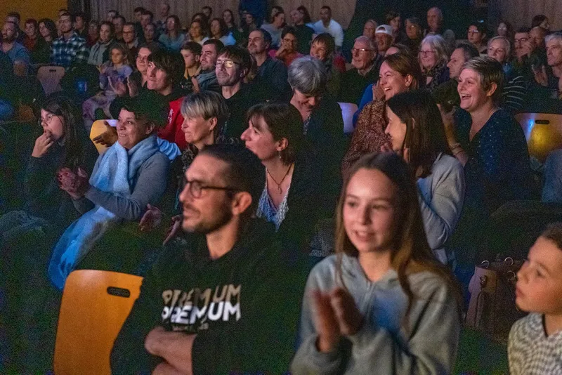 Spectateurs amusés au premier rang d'un spectacle d'hypnose, qui applaudissent en souriant